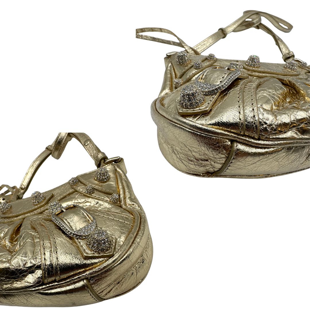 angoli Borsa Balenciaga in pelle dorata con parti metalliche dorate, impreziosita da borchie con cristalli incastonati; munita di un manico in catena e una tracolla regolabile. Completa di dustbag, di lusso, originale, ottime condizioni. 