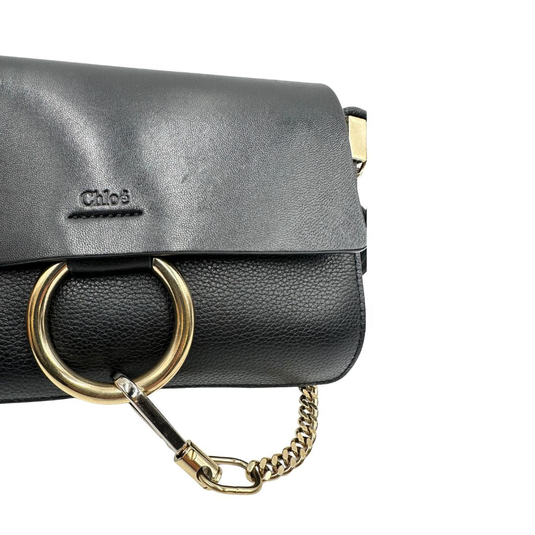 Borsa Chloé Faye in pelle martellata nera con parti metalliche dorate, munita di una tracolla regolabile. Impreziosita di una chiusura principale con gancio con l'iconico anello sul davanti, collegato a una piccola catena a moschettone. Indossabile a tracolla .Originale, usata, di lusso, in ottime condizioni.