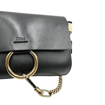 Borsa Chloé Faye in pelle martellata nera con parti metalliche dorate, munita di una tracolla regolabile. Impreziosita di una chiusura principale con gancio con l'iconico anello sul davanti, collegato a una piccola catena a moschettone. Indossabile a tracolla .Originale, usata, di lusso, in ottime condizioni.