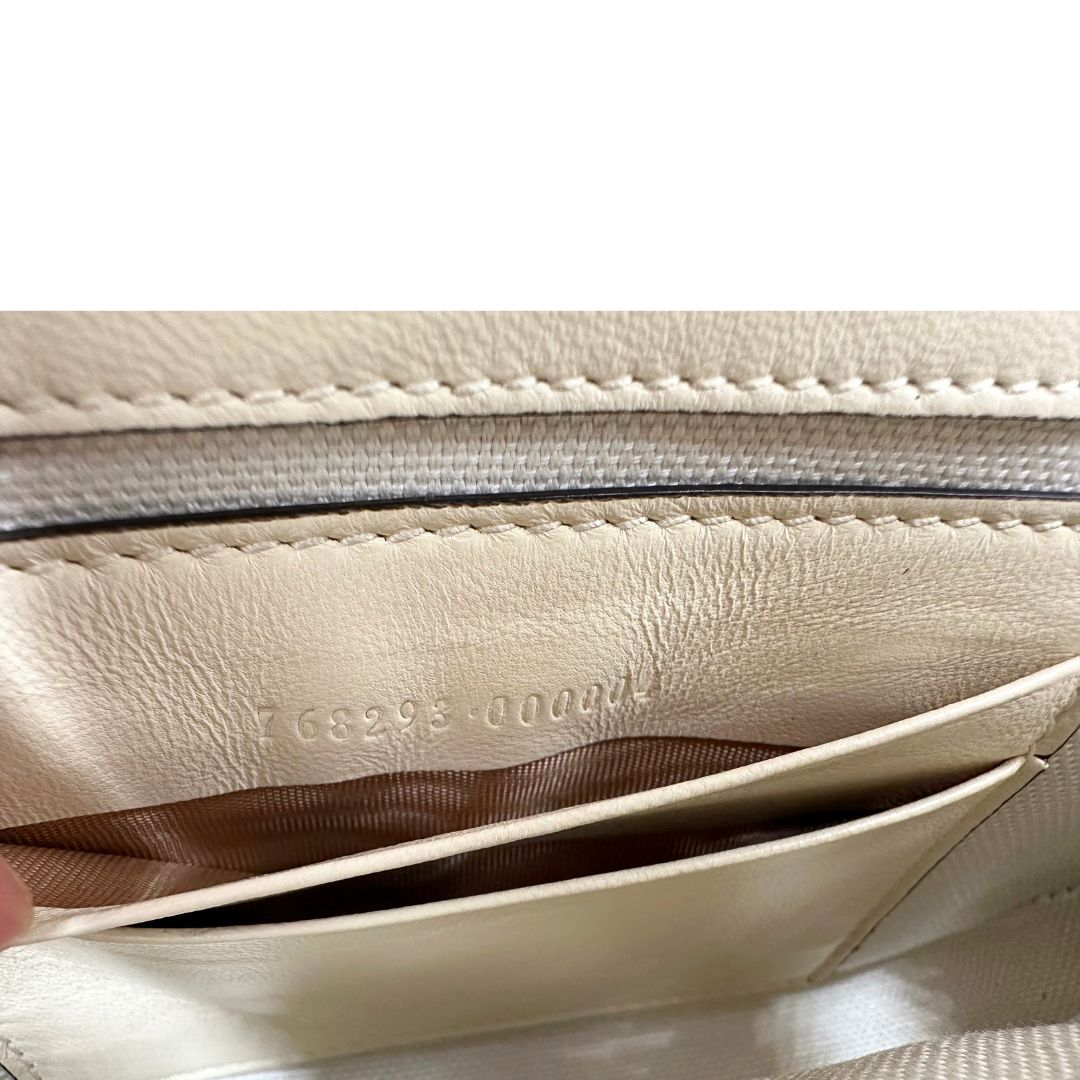 Codice di una Borsa Gucci GG Marmont in pelle matelassé color bianco latte, caratterizzata dalla classica trapuntatura a chevron e dagli iconici dettagli GG in metallo dorato anticato. Dotata di tracolla a catena amovibile. Presente un pouch portamonete con zip rimovibile. Completa di dustbag. Originale, usata, di lusso, in condizioni eccellenti.