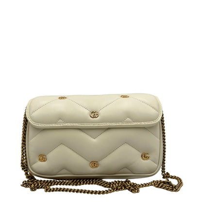 Retro di una Borsa Gucci GG Marmont in pelle matelassé color bianco latte, caratterizzata dalla classica trapuntatura a chevron e dagli iconici dettagli GG in metallo dorato anticato. Dotata di tracolla a catena amovibile. Presente un pouch portamonete con zip rimovibile. Completa di dustbag. Originale, usata, di lusso, in condizioni eccellenti.