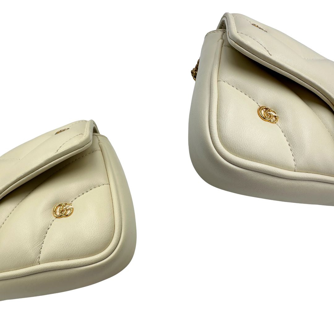 Angoli di una Borsa Gucci GG Marmont in pelle matelassé color bianco latte, caratterizzata dalla classica trapuntatura a chevron e dagli iconici dettagli GG in metallo dorato anticato. Dotata di tracolla a catena amovibile. Presente un pouch portamonete con zip rimovibile. Completa di dustbag. Originale, usata, di lusso, in condizioni eccellenti.