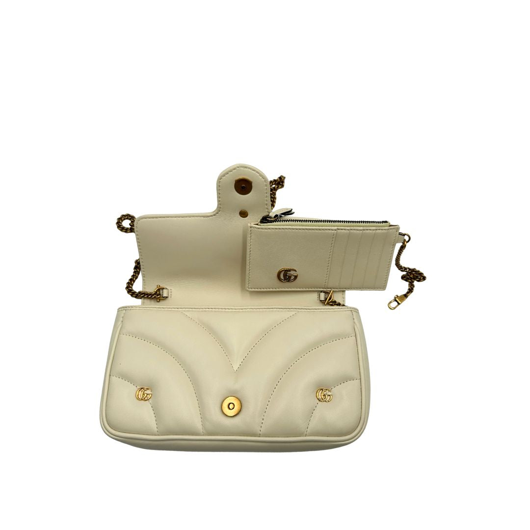 Interno di una Borsa Gucci GG Marmont in pelle matelassé color bianco latte, caratterizzata dalla classica trapuntatura a chevron e dagli iconici dettagli GG in metallo dorato anticato. Dotata di tracolla a catena amovibile. Presente un pouch portamonete con zip rimovibile. Completa di dustbag. Originale, usata, di lusso,in condizioni eccellenti.