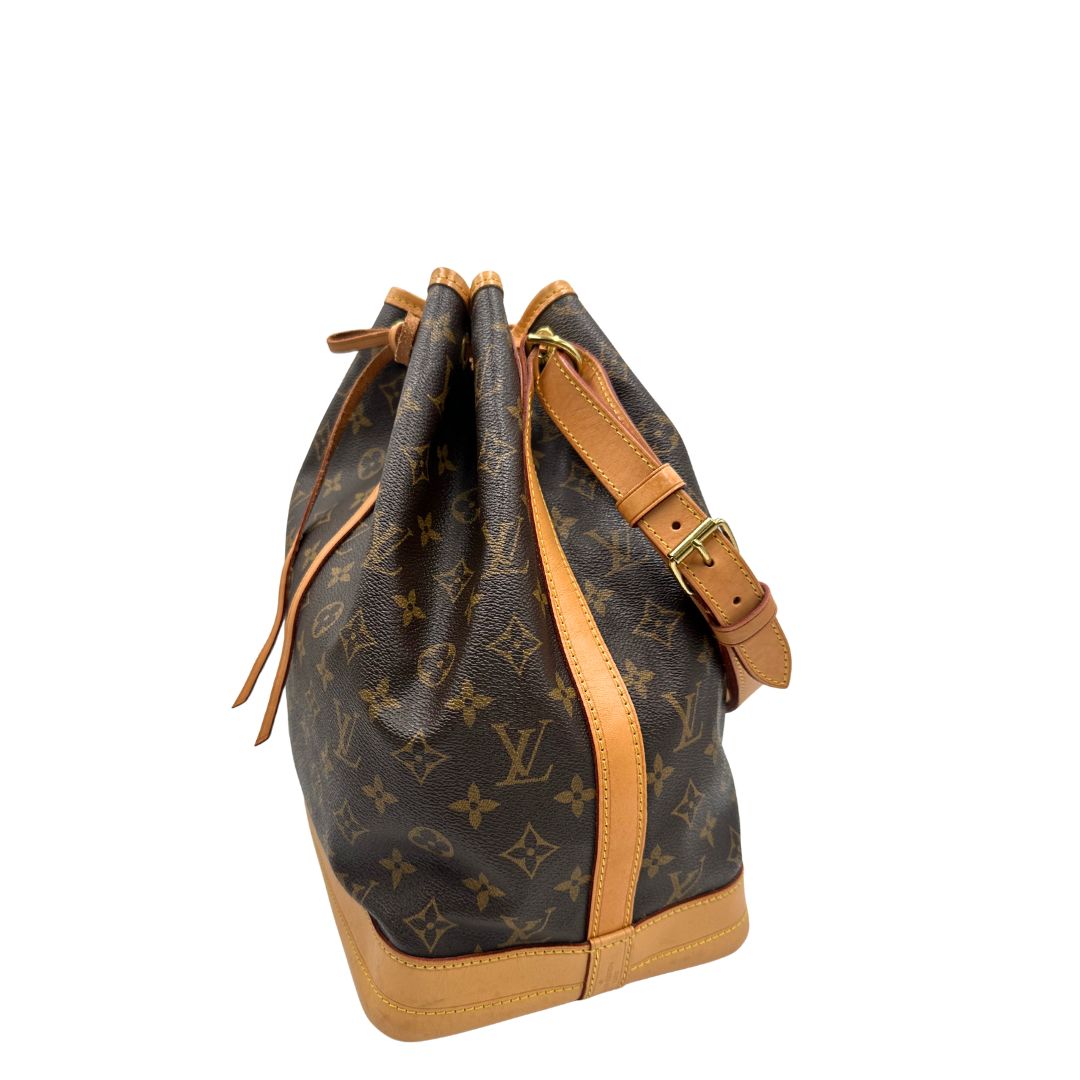 Lato sinistro di un Secchiello Noé Louis Vuitton in canvas marrone monogram con finiture in vacchetta naturale, tracolla regolabile con fibbia e parti metalliche dorate. Completo di dustbag. Originale, usato, di lusso, in ottime condizioni