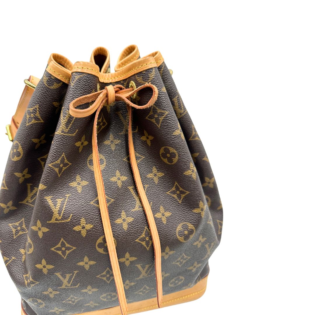 Chiusura di un Secchiello Noé Louis Vuitton in canvas marrone monogram con finiture in vacchetta naturale, tracolla regolabile con fibbia e parti metalliche dorate. Completo di dustbag. Originale, usato, di lusso, in ottime condizioni