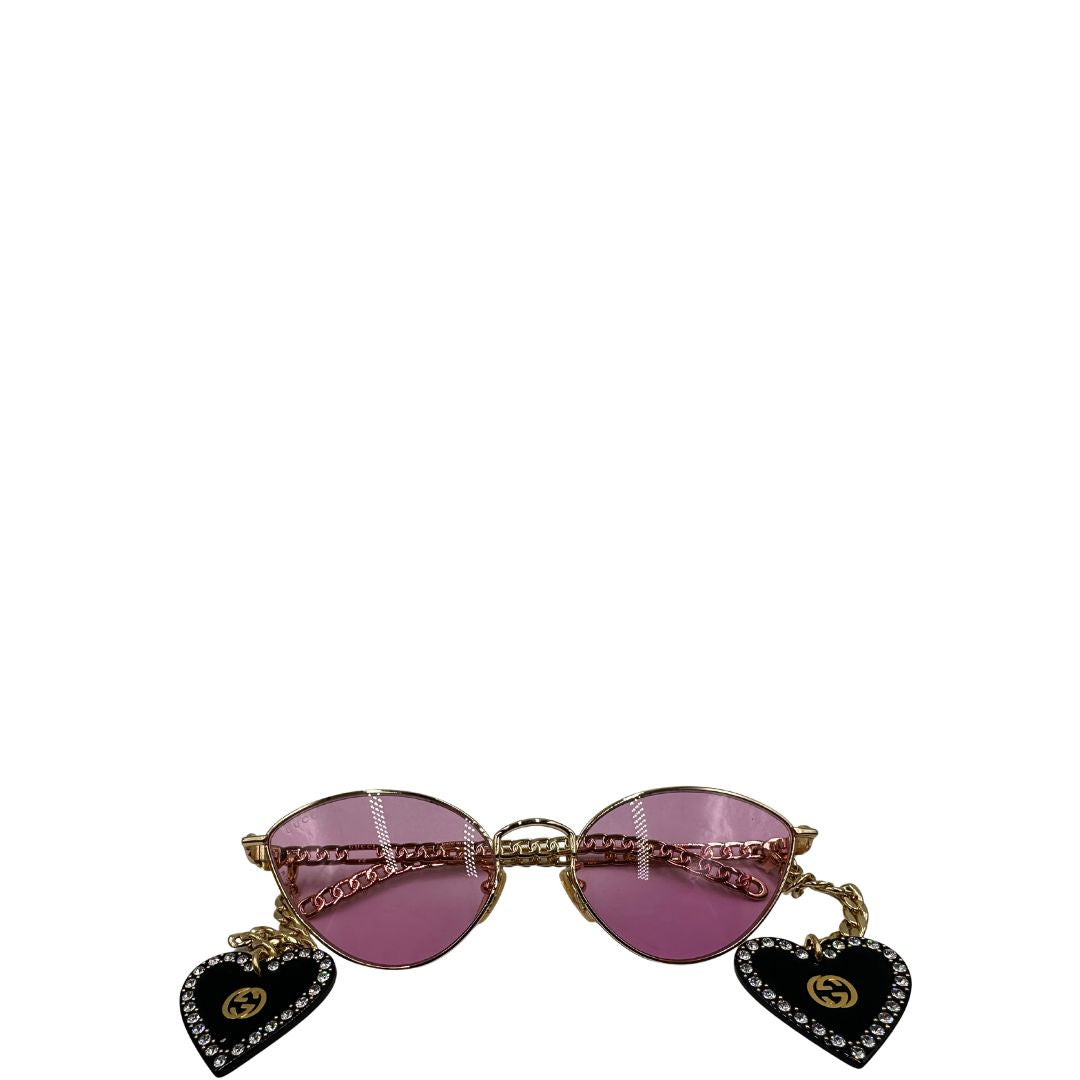 Occhiali da sole Gucci in metallo dorato e lenti rosa, muniti di due pendenti con cuore amovibili. Completi di sacchetto antipolvere, di lusso, originale, ottime condizioni. 
