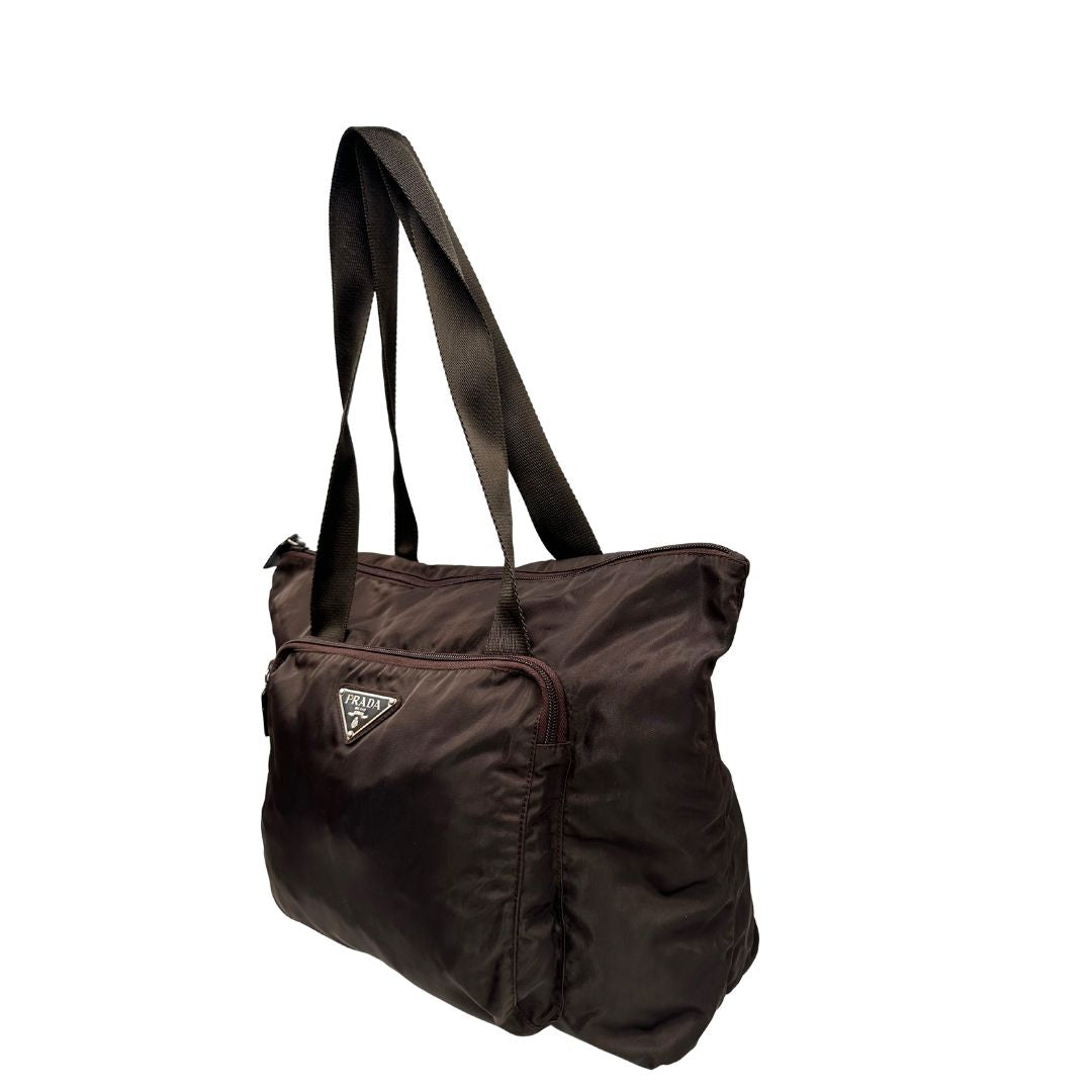 lato Borsa Prada in nylon marrone scuro con parti metalliche argentate , munita di doppi manici in tessuto, indossabile a spalla.