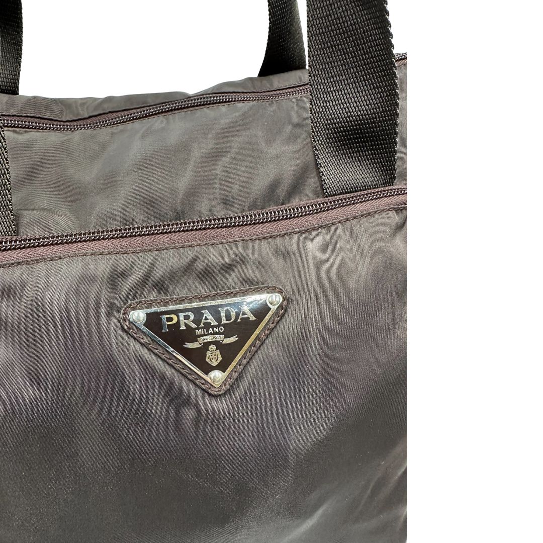 logo Borsa Prada in nylon marrone scuro con parti metalliche argentate , munita di doppi manici in tessuto, indossabile a spalla.