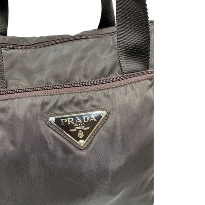 logo Borsa Prada in nylon marrone scuro con parti metalliche argentate , munita di doppi manici in tessuto, indossabile a spalla.