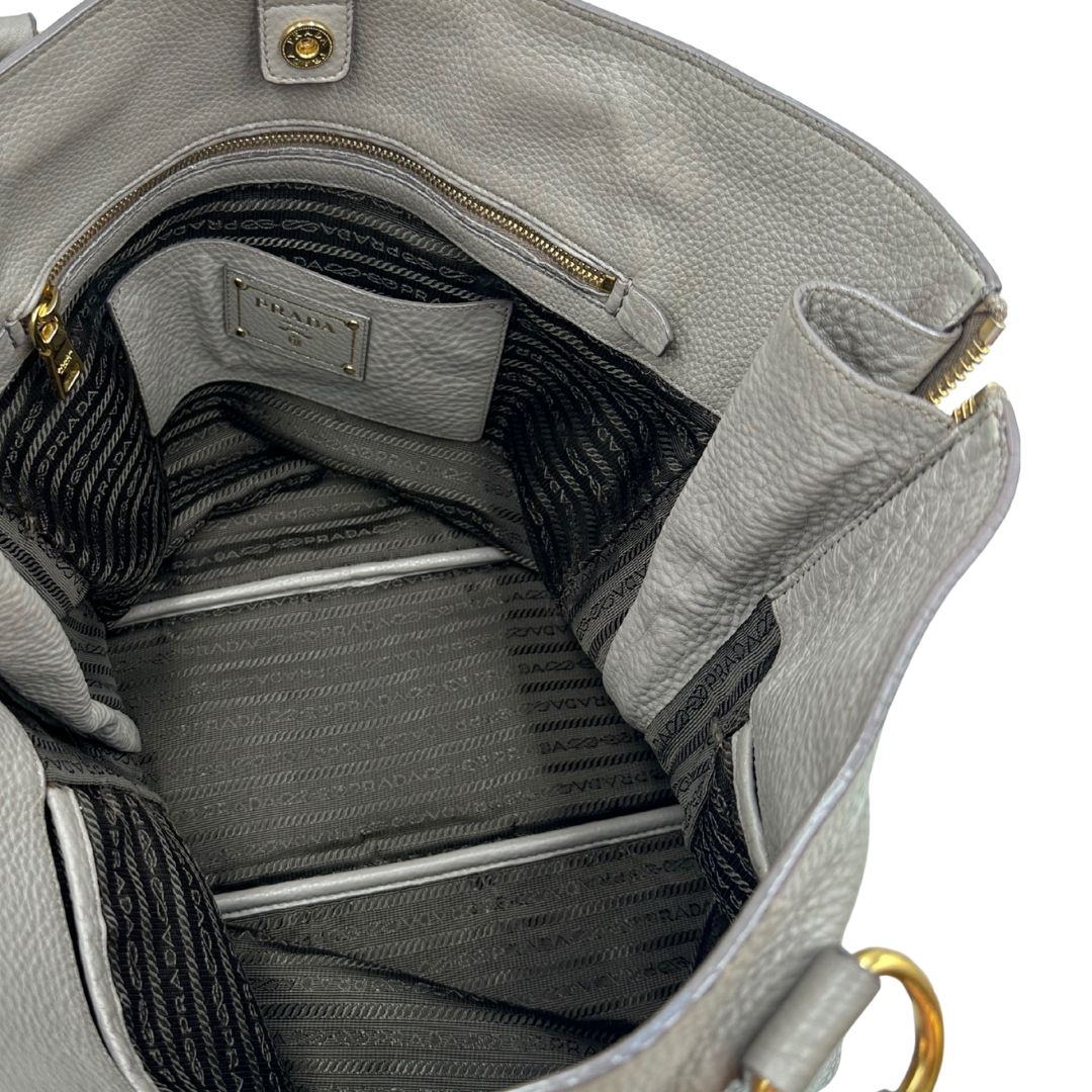interno Borsa Prada in pelle grigia martellata con parti metalliche dorate; munita di cerniere laterali e doppi manici, indossabile a spalla, di lusso, originale, ottime condizioni, usata. 