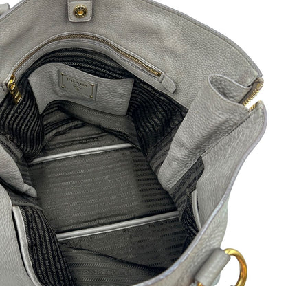 interno Borsa Prada in pelle grigia martellata con parti metalliche dorate; munita di cerniere laterali e doppi manici, indossabile a spalla, di lusso, originale, ottime condizioni, usata. 