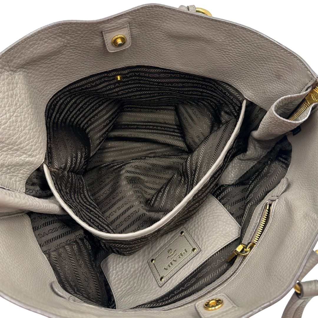 interno Borsa Prada in pelle grigia martellata con parti metalliche dorate; munita di cerniere laterali e doppi manici, indossabile a spalla, di lusso, originale, ottime condizioni, usata. 
