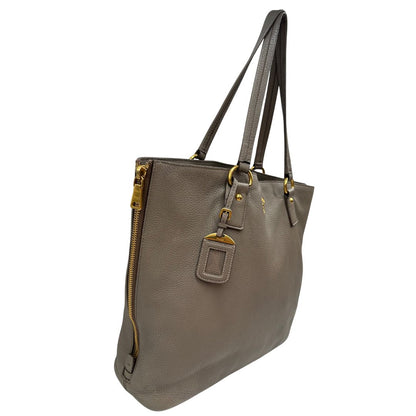 lato Borsa Prada in pelle grigia martellata con parti metalliche dorate; munita di cerniere laterali e doppi manici, indossabile a spalla, di lusso, originale, ottime condizioni, usata. 