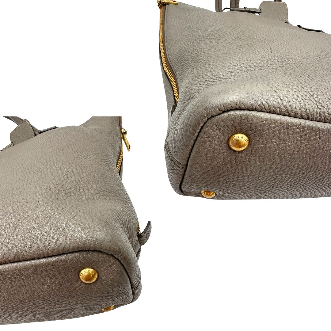 angoli Borsa Prada in pelle grigia martellata con parti metalliche dorate; munita di cerniere laterali e doppi manici, indossabile a spalla, di lusso, originale, ottime condizioni, usata. 