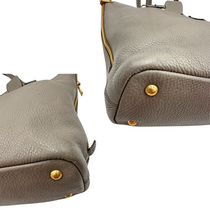 angoli Borsa Prada in pelle grigia martellata con parti metalliche dorate; munita di cerniere laterali e doppi manici, indossabile a spalla, di lusso, originale, ottime condizioni, usata. 