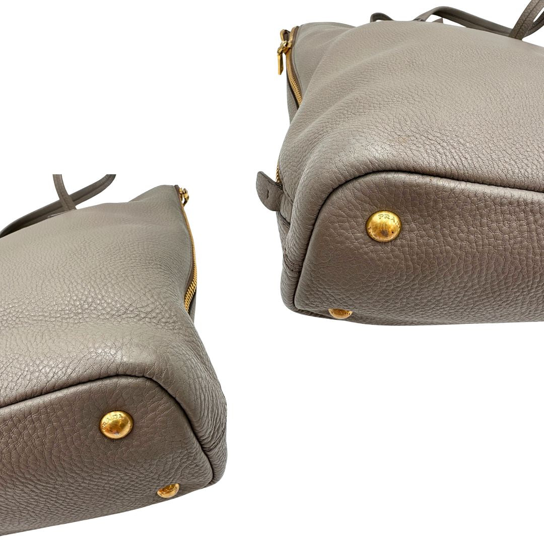 angoli Borsa Prada in pelle grigia martellata con parti metalliche dorate; munita di cerniere laterali e doppi manici, indossabile a spalla, di lusso, originale, ottime condizioni, usata.