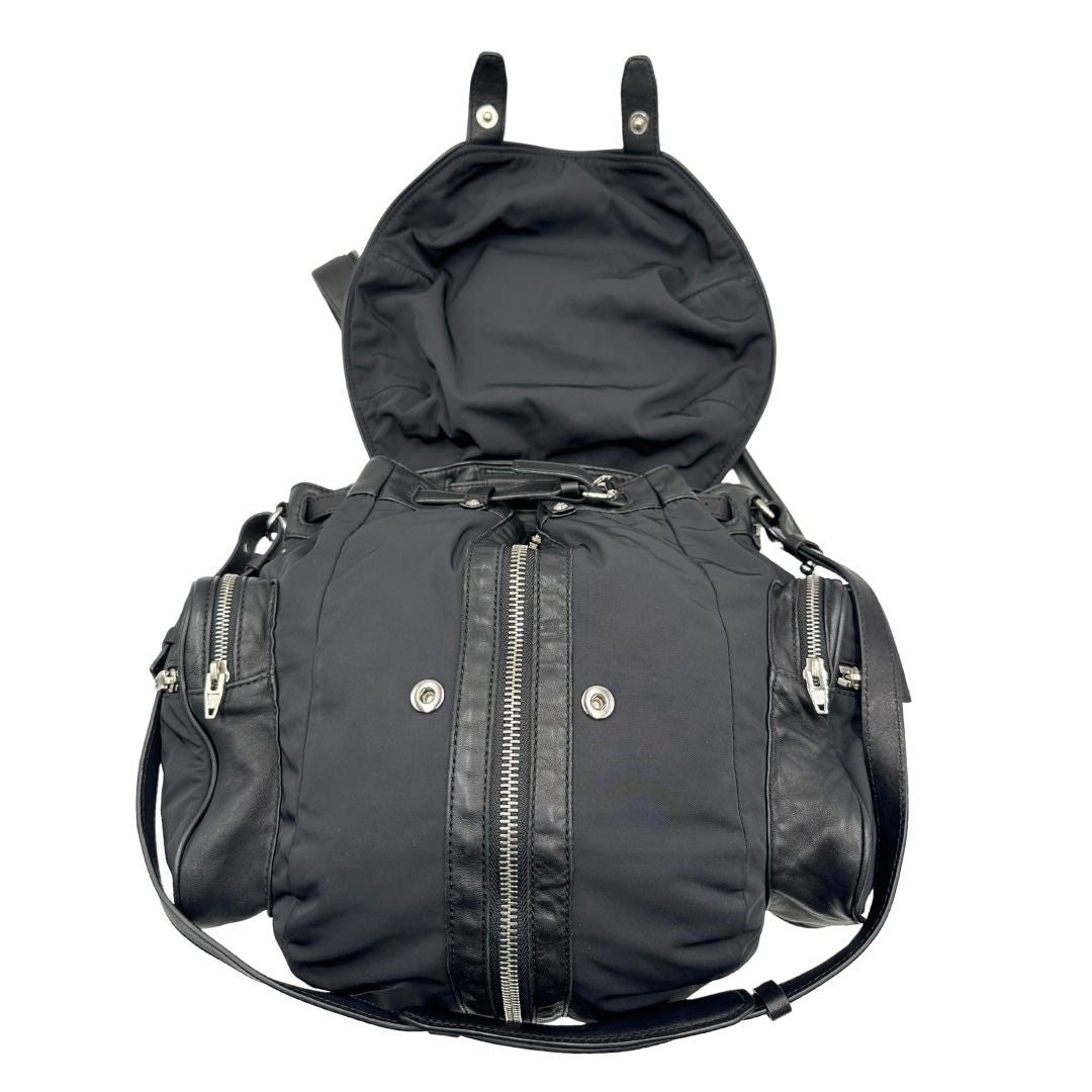 Apertura di uno zaino Alexander Wang in nylon nero e finiture in pelle tono su tono. Parti metalliche argentate; munito di doppie bretelle e una tracolla. Indossabile come zaino o a tracolla.