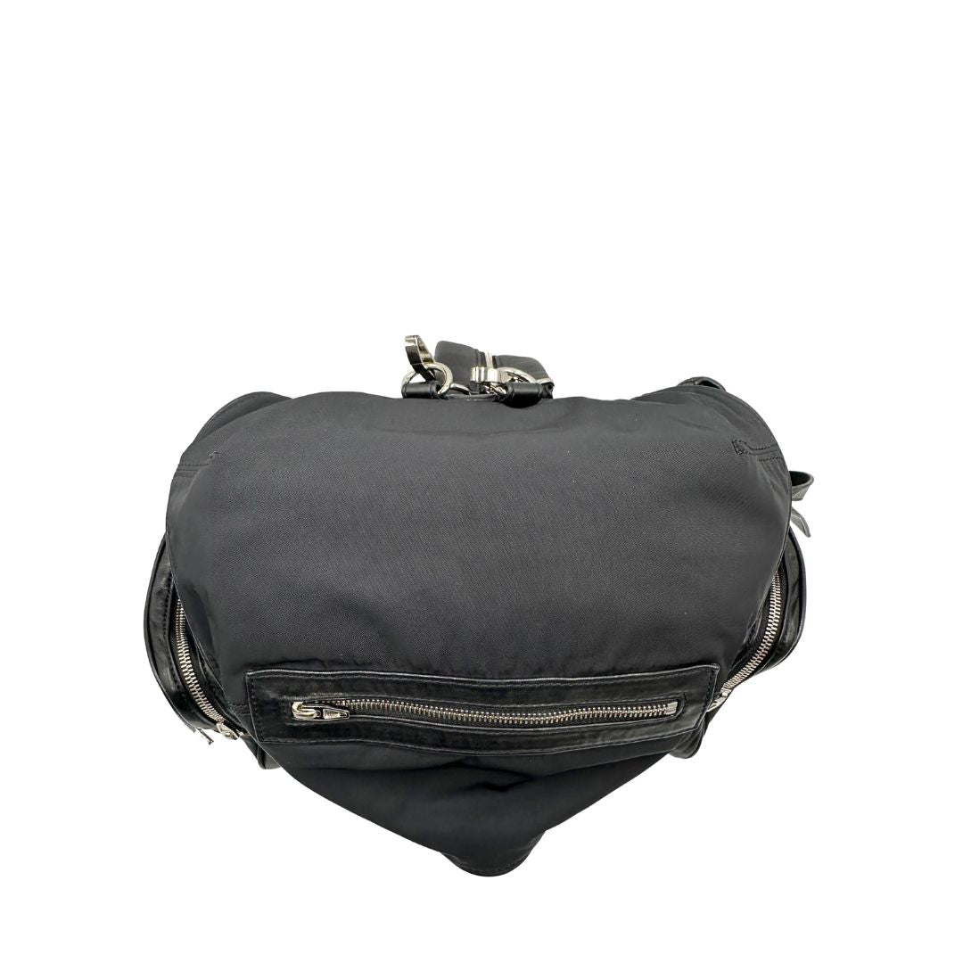 Vista superiore di uno zaino Alexander Wang in nylon nero e finiture in pelle tono su tono. Parti metalliche argentate; munito di doppie bretelle e una tracolla. Indossabile come zaino o a tracolla.