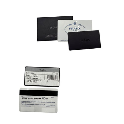 Crtellini di una Borsa Prada in nylon Grigia con finiture in pelle nera e parti metalliche dorate; munita di una tracolla in tessuto regolabile e tag porta address. Originale, usata, di lusso in ottime condizioni.