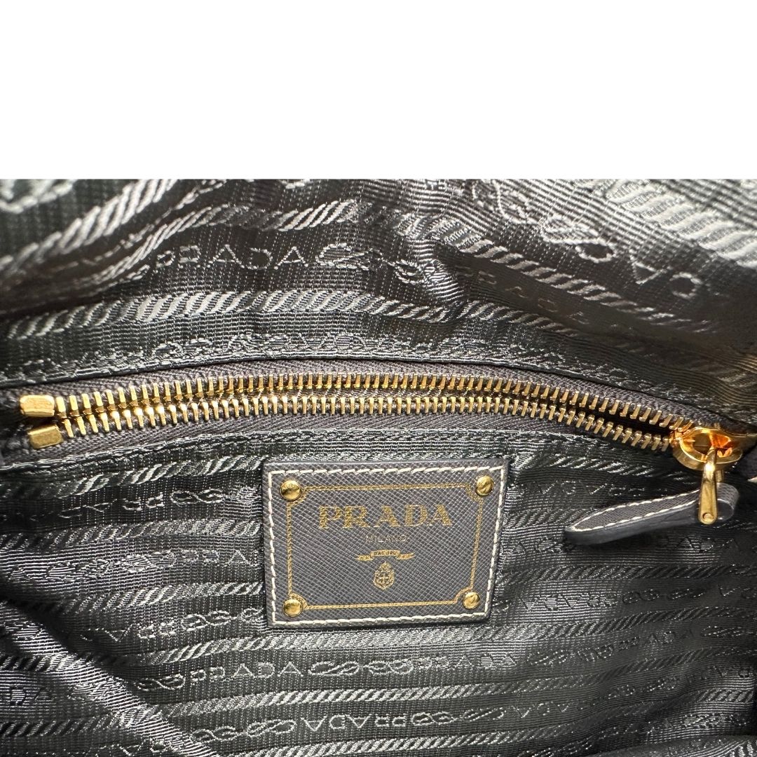 Interno di una Borsa Prada in nylon Grigia con finiture in pelle nera e parti metalliche dorate; munita di una tracolla in tessuto regolabile e tag porta address. Originale, usata, di lusso in ottime condizioni.