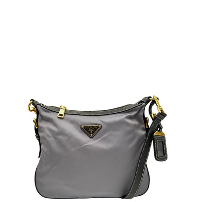 Front di una Borsa Prada in nylon Grigia con finiture in pelle nera e parti metalliche dorate; munita di una tracolla in tessuto regolabile e tag porta address. Originale, usata, di lusso in ottime condizioni.