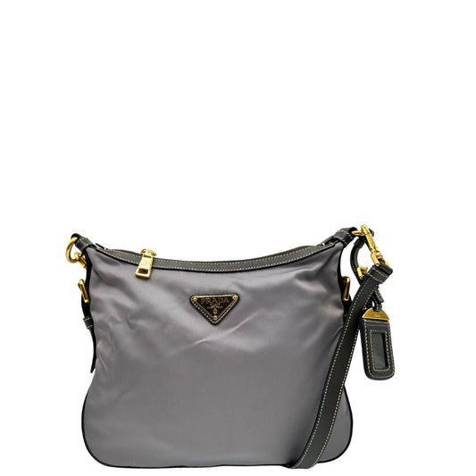 Front di una Borsa Prada in nylon Grigia con finiture in pelle nera e parti metalliche dorate; munita di una tracolla in tessuto regolabile e tag porta address. Originale, usata, di lusso in ottime condizioni.
