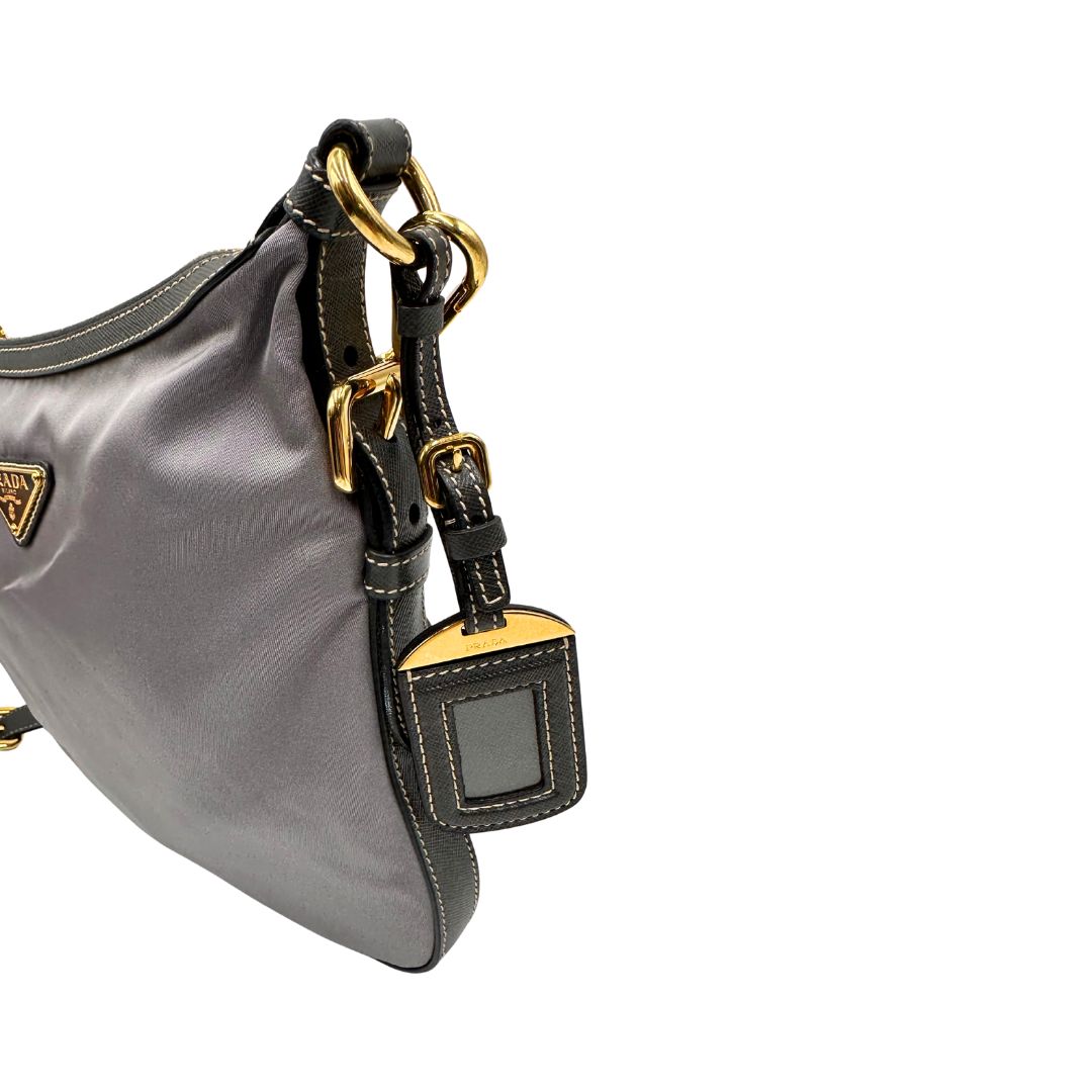 Borsa Prada in nylon Grigia con finiture in pelle nera e parti metalliche dorate; munita di una tracolla in tessuto regolabile e tag porta address. Originale, usata, di lusso in ottime condizioni.