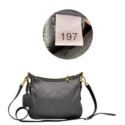 Retro di una Borsa Prada in nylon Grigia con finiture in pelle nera e parti metalliche dorate; munita di una tracolla in tessuto regolabile e tag porta address. Originale, usata, di lusso in ottime condizioni.