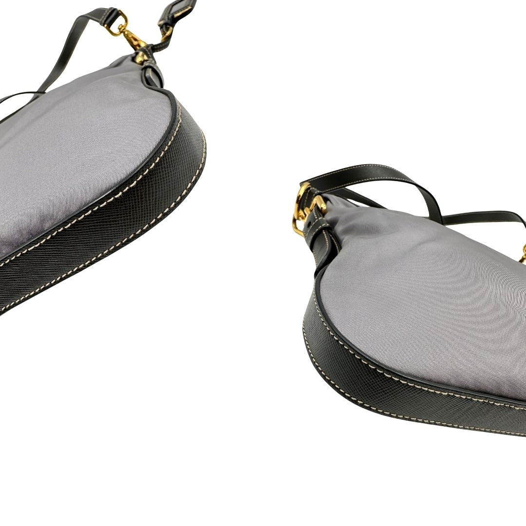 Angoli di una Borsa Prada in nylon Grigia con finiture in pelle nera e parti metalliche dorate; munita di una tracolla in tessuto regolabile e tag porta address. Originale, usata, di lusso in ottime condizioni.