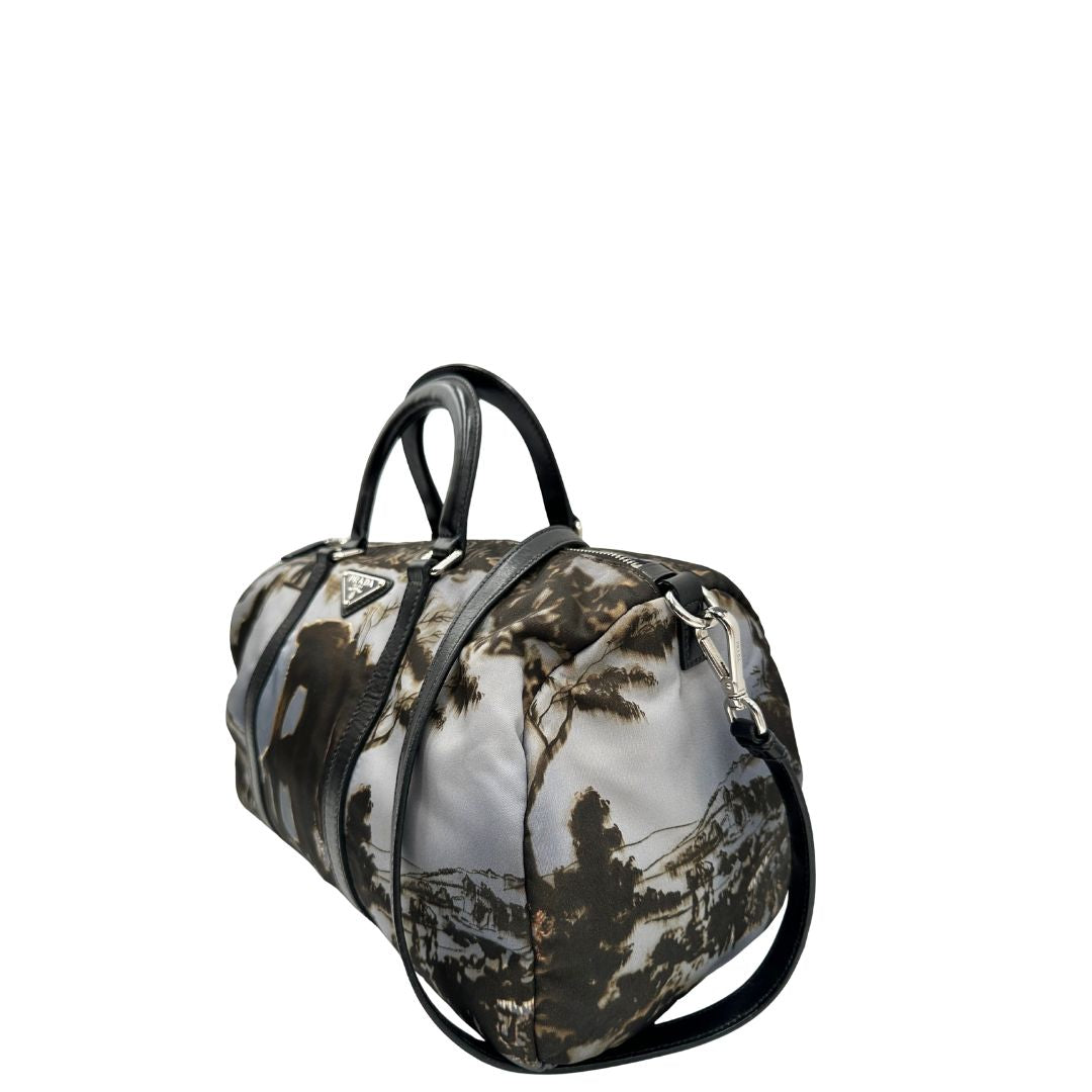 lato Borsa Prada in nylon con grafica decorativa e finiture in pelle nere e parti metalliche argentate; munita di doppi manici stondati e una tracolla amovibile e regolabile. Completa di corredo, di lusso, originale, ottime condizioni. 