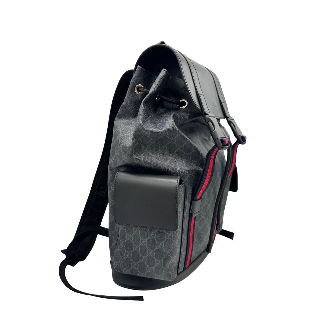 Lato destro di un Zaino Gucci in canvas grigio GG con finiture in pelle neri e parti metalliche argentate. Iconica striscia Web in blu/rosso sul front, munito di un manico singolo, Bretelle imbottite regolabili e patta con moschettoni a scatto. Completo di dustbag. Originale, usato, di lusso, in condizioni eccellenti.