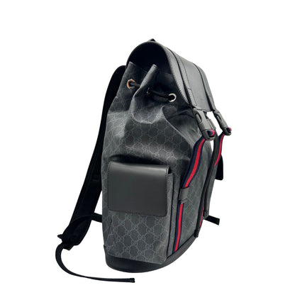 Lato destro di un Zaino Gucci in canvas grigio GG con finiture in pelle neri e parti metalliche argentate. Iconica striscia Web in blu/rosso sul front, munito di un manico singolo, Bretelle imbottite regolabili e patta con moschettoni a scatto. Completo di dustbag. Originale, usato, di lusso, in condizioni eccellenti.