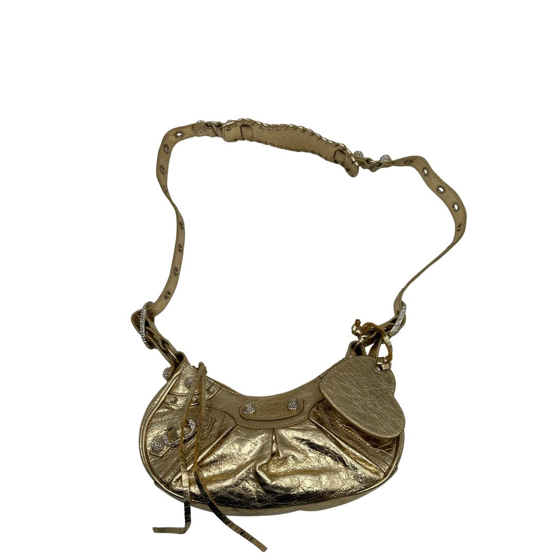 Borsa Balenciaga in pelle dorata con parti metalliche dorate, impreziosita da borchie con cristalli incastonati; munita di una tracolla regolabile. Completa di dustbag, di lusso, originale, ottime condizioni. 