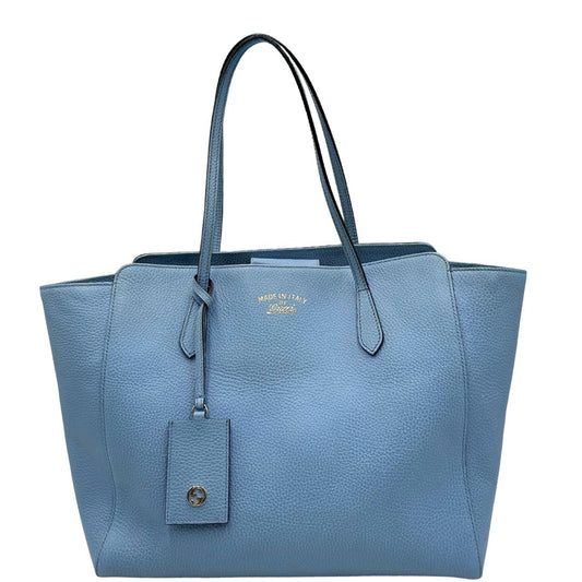 Front di una Borsa Gucci in pelle martellata color Blu fiordaliso con incisioni dorate munita di due manici e tag porta adress. Indossabile a spalla. Completa di cartellino. Originale, usata, di lusso, in ottime condizioni.