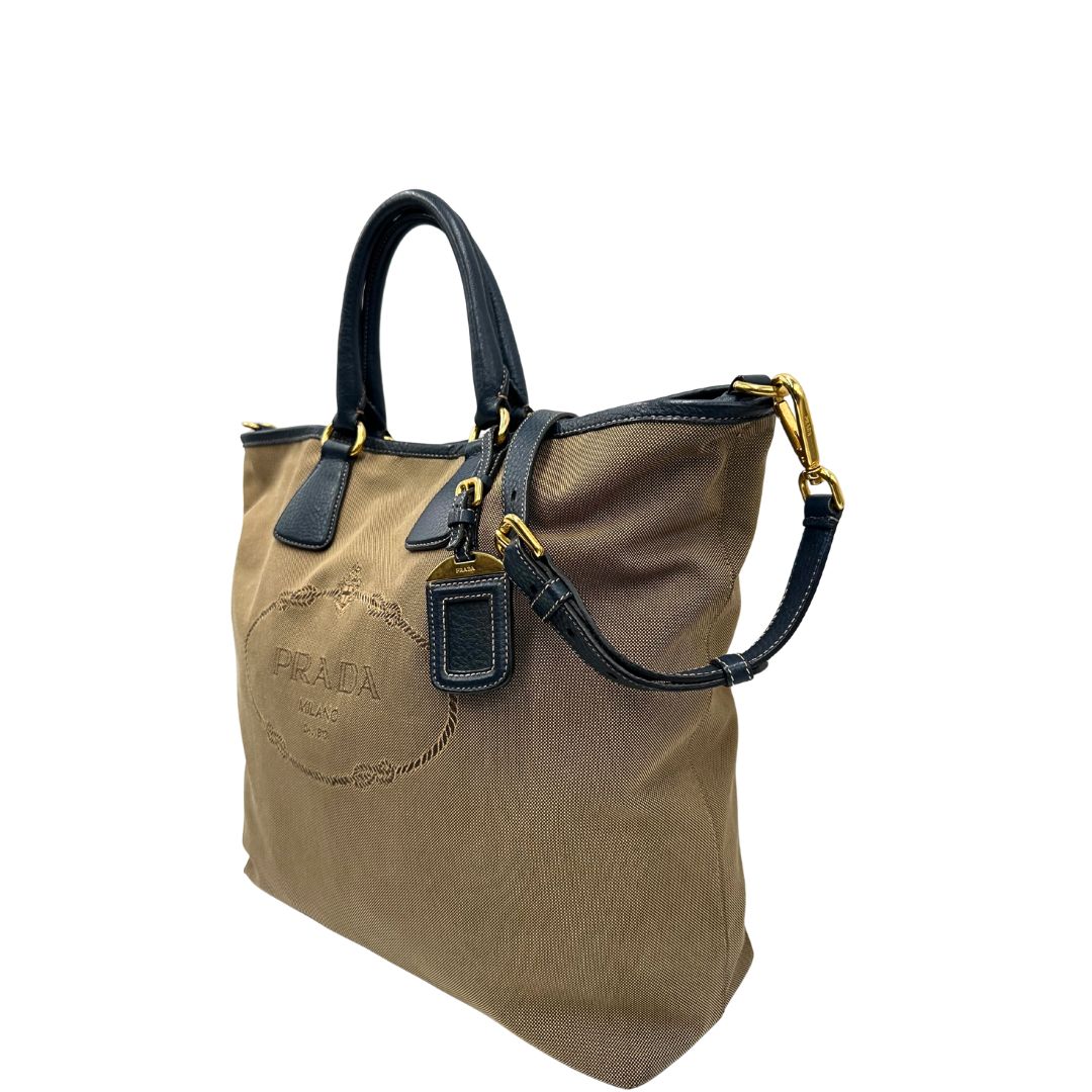 lato  Borsa Prada in tessuto color corda con logo Jacquard sul front, finiture in pelle blu e parti metalliche dorate; munita di doppi manici e una tracolla amovibile e regolabile. Completa di dustbag, ottime condizioni, usata. 