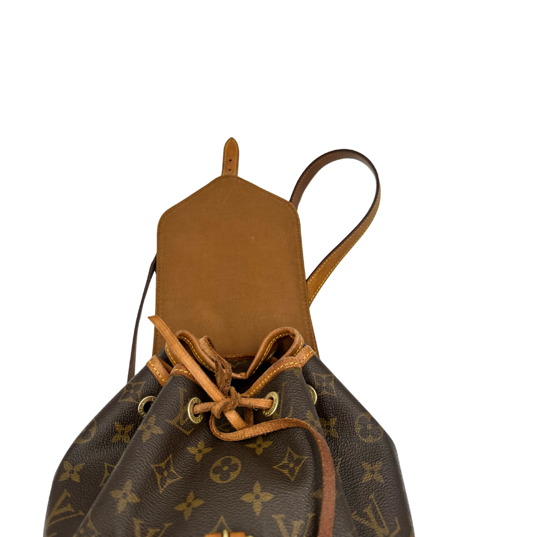 Zaino Montsouris PM in canvas marrone monogram con finiture in vacchetta naturale e parti metalliche dorate, munito di un Anello da portare a mano e una tracolle in vacchetta regolabile con fibbie. Originale, usato , di lusso, in ottime condizioni.