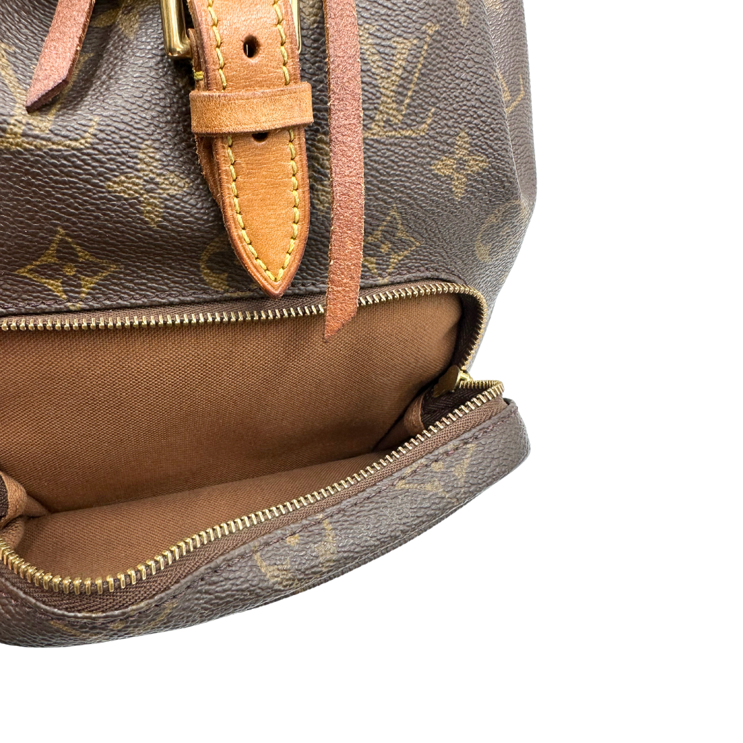 Tasca esterna di un Zaino Montsouris PM in canvas marrone monogram con finiture in vacchetta naturale e parti metalliche dorate, munito di un Anello da portare a mano e una tracolle in vacchetta regolabile con fibbie. Originale, usato , di lusso, in ottime condizioni.