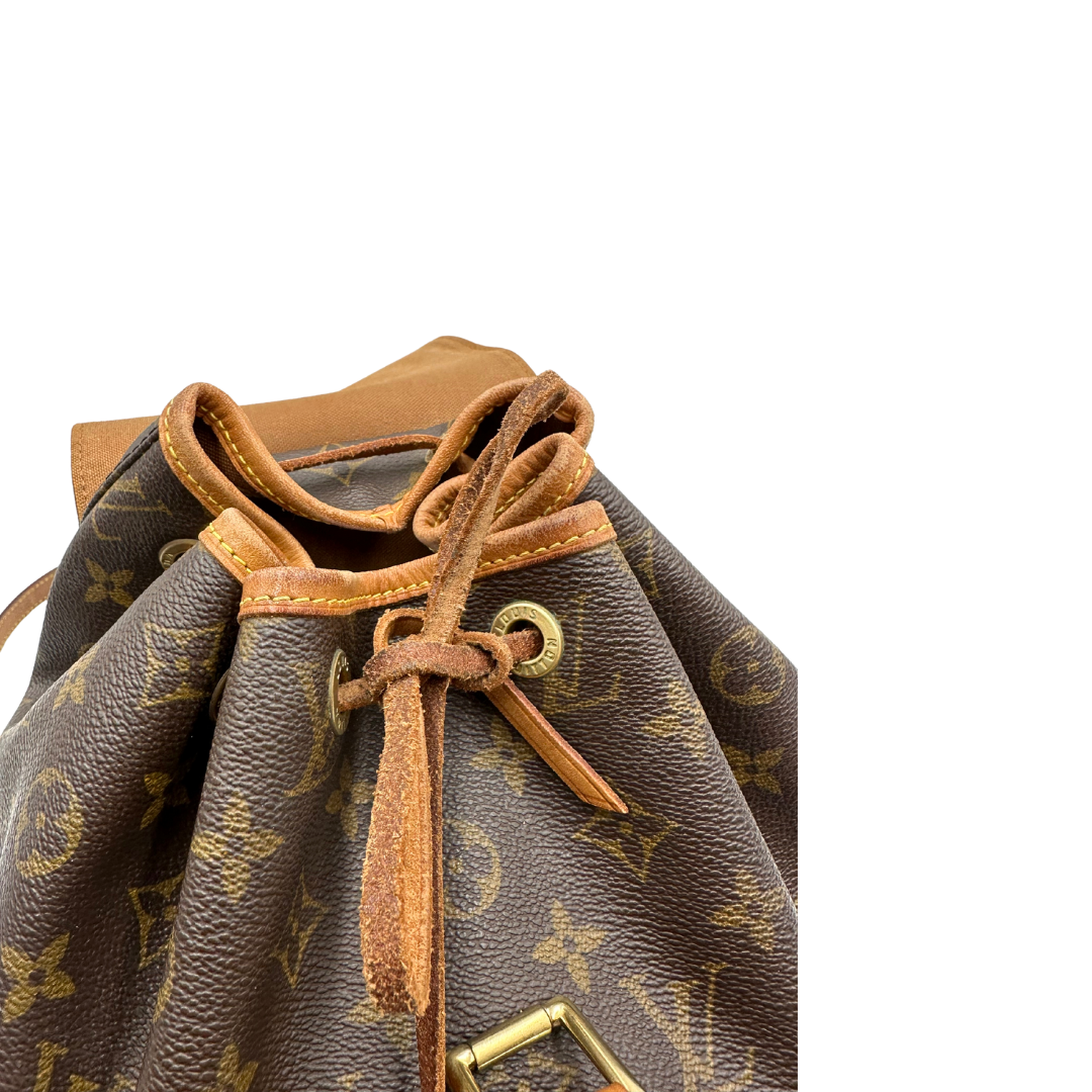 Chiusura di un Zaino Montsouris PM in canvas marrone monogram con finiture in vacchetta naturale e parti metalliche dorate, munito di un Anello da portare a mano e una tracolle in vacchetta regolabile con fibbie. Originale, usato , di lusso, in ottime condizioni.