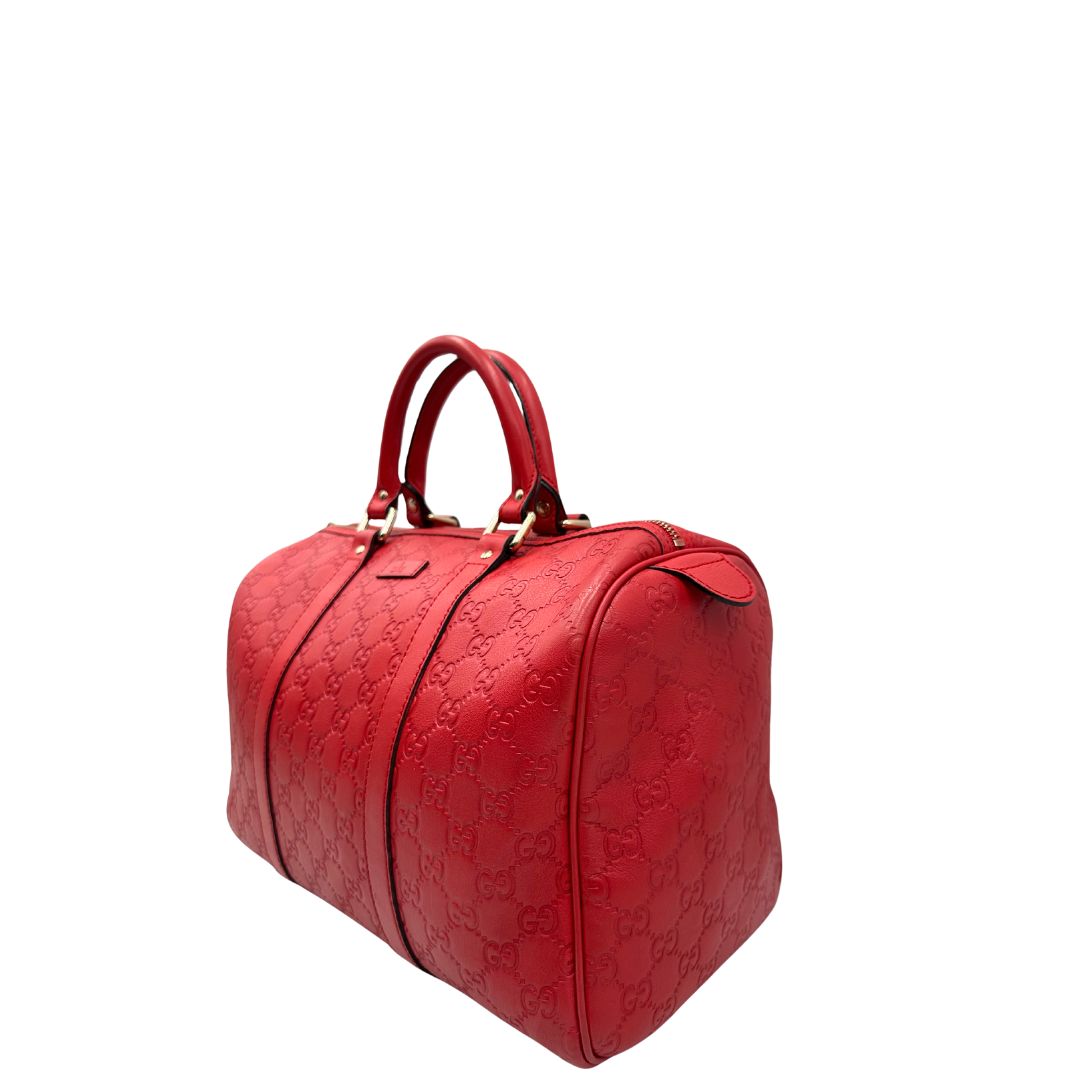 Lato sinistro di una Borsa Gucci in pelle color rosso GG con parti metalliche dorate; munita di doppi manici stondati , da portare a mano. Completa di dustbag. Originale, usata, di lusso, in ottime condizioni.