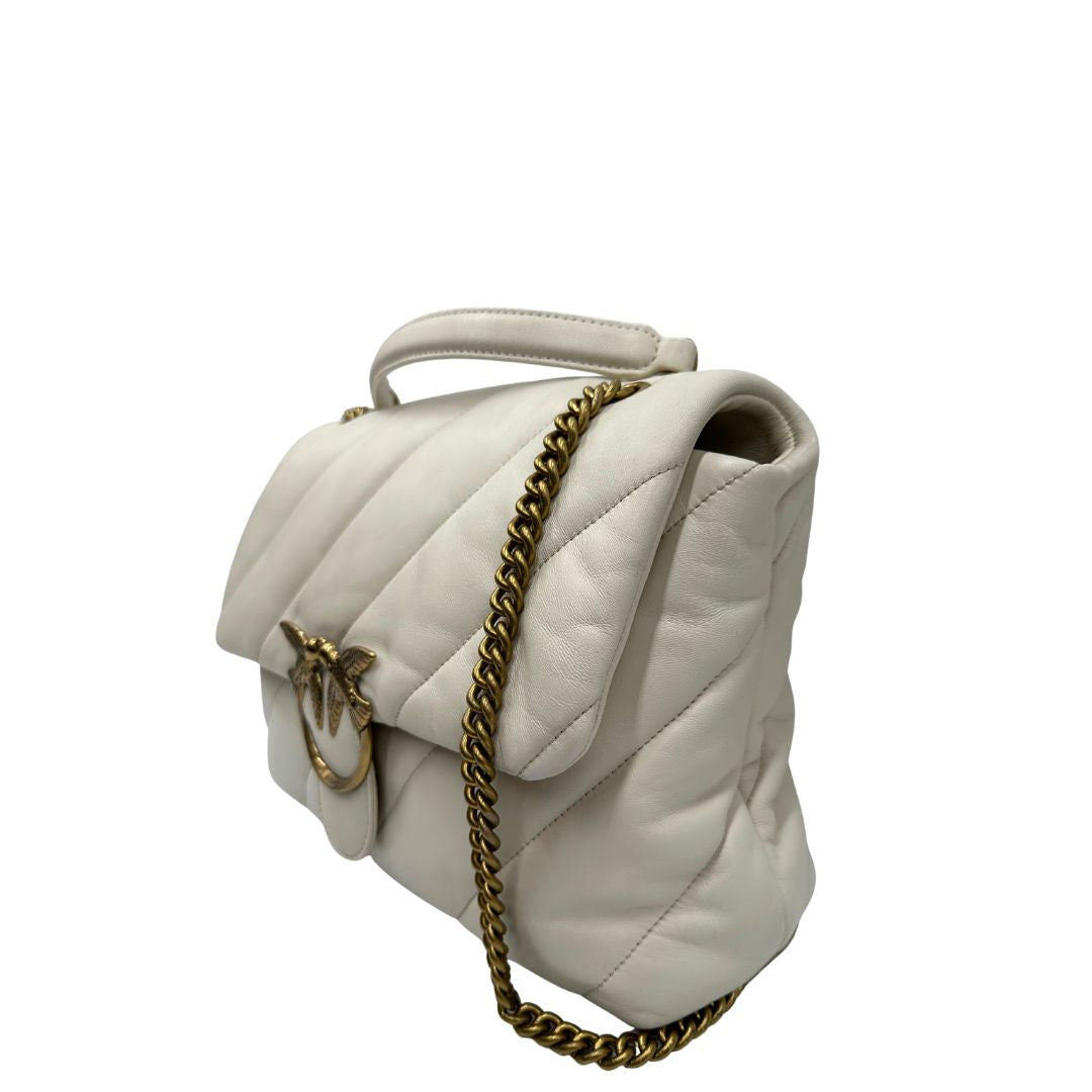 Lato sinistro di una Borsa Pinko in pelle trapuntata color bianco gesso con parti metalliche dorate; munita di una tracolla in catena scorrevole e spallaccio in pelle. Indossabile a spalla oppure a tracolla. Originale, usata, di lusso, in condizioni buone.