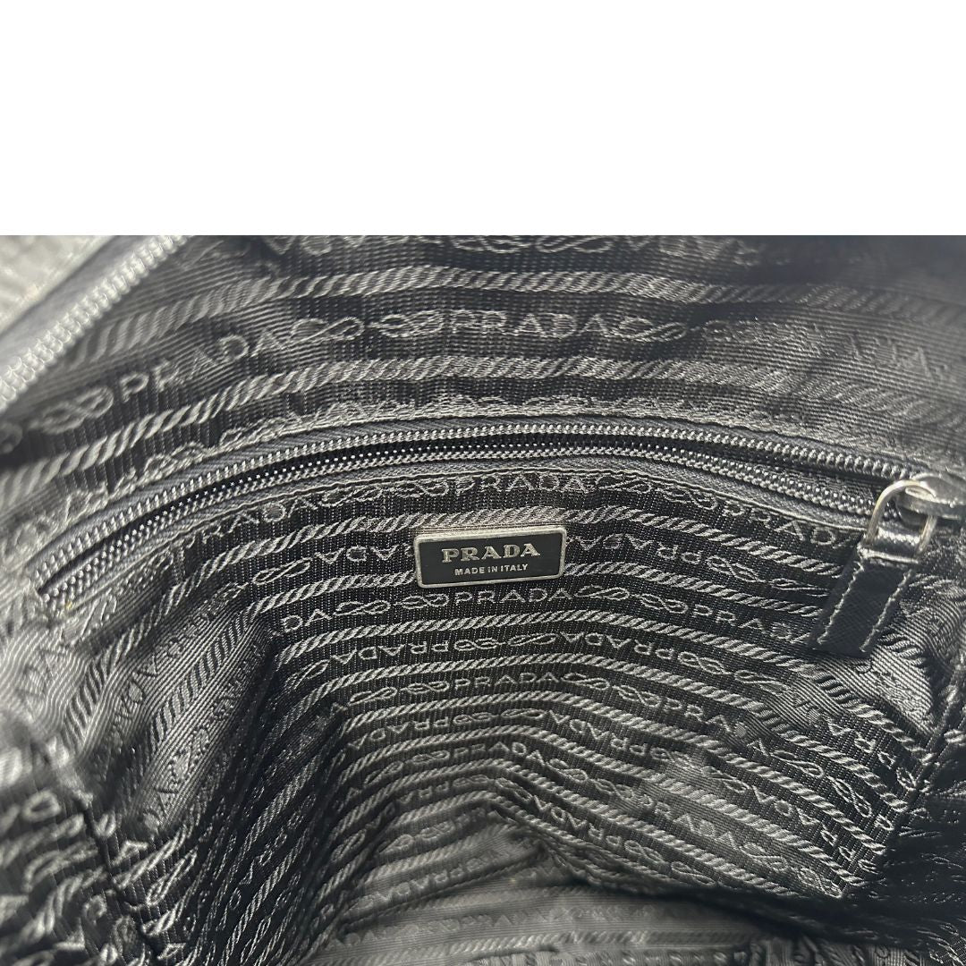 Interno di una Borsa Prada in nylon nero con finiture in pelle tono su tono e parti metalliche argentate; munita di una tracolla in tessuto regolabile. Originale, usata, di lusso, in ottime condizioni