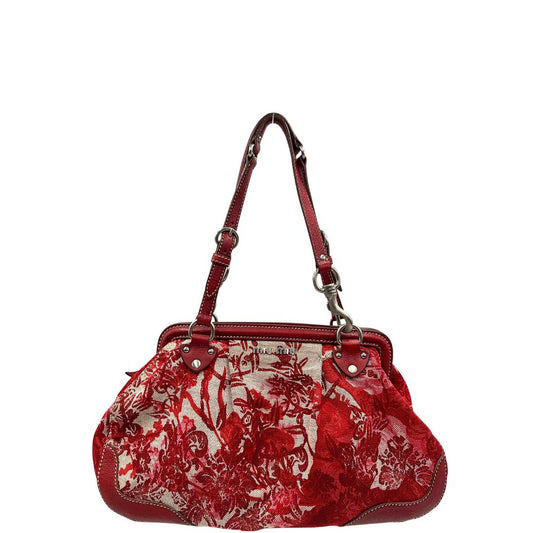 Borsa Miu Miu in tessuto jacquard rosso e beige in trama floreale, con finiture in pelle rosse e parti metalliche argentate. Presenta doppi manici leggermente regolabili e chiusura con zip. Indossabile a spalla.