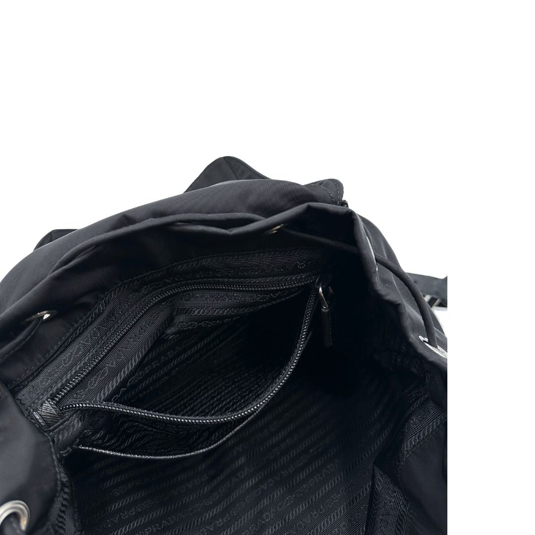 Interno di un Zaino Prada in tessuto nylon nero e finiture in pelle saffiano tono su tono. Parti metalliche argentate; munito di doppie bretelle in tessuto regolabili. Completo di corredo e card d'autenticità. Originale, usato, di lusso, in condizioni eccellenti.