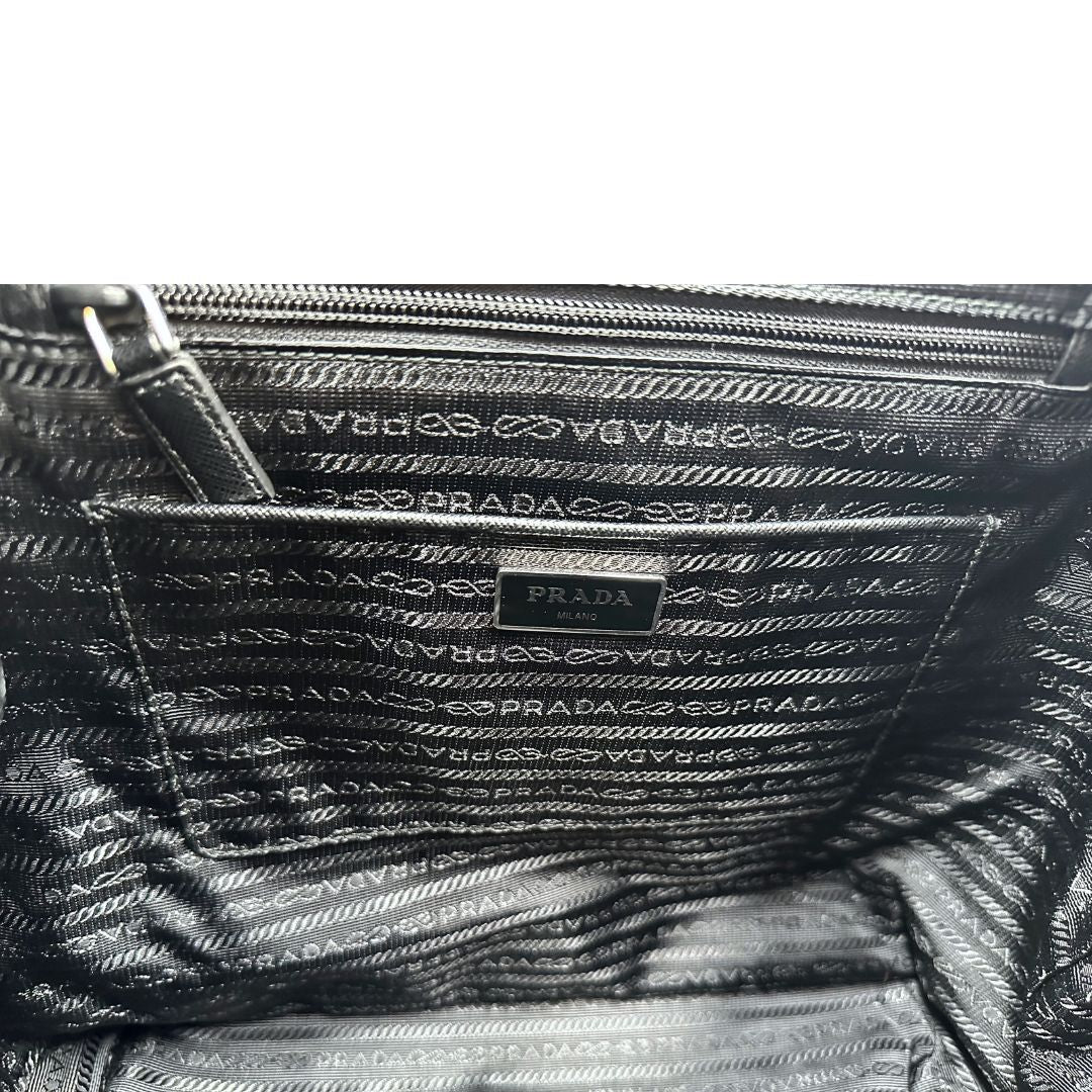 Interno di un Zaino Prada in tessuto nylon nero e finiture in pelle saffiano tono su tono. Parti metalliche argentate; munito di doppie bretelle in tessuto regolabili. Completo di corredo e card d'autenticità. Originale, usato, di lusso, in condizioni eccellenti.
