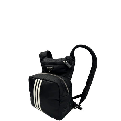 Laterale destro di uno zaino Prada x Adidas in Re-Nylon con chiusura a zip. Struttura con tasca frontale a zip e tasca superiore integrata negli spallacci. Spallacci regolabili con imbottitura e pannello posteriore in mesh. Dettagli con logo triangolo Prada sul lato superiore e branding Prada Re-Nylon e Adidas sul fianco.