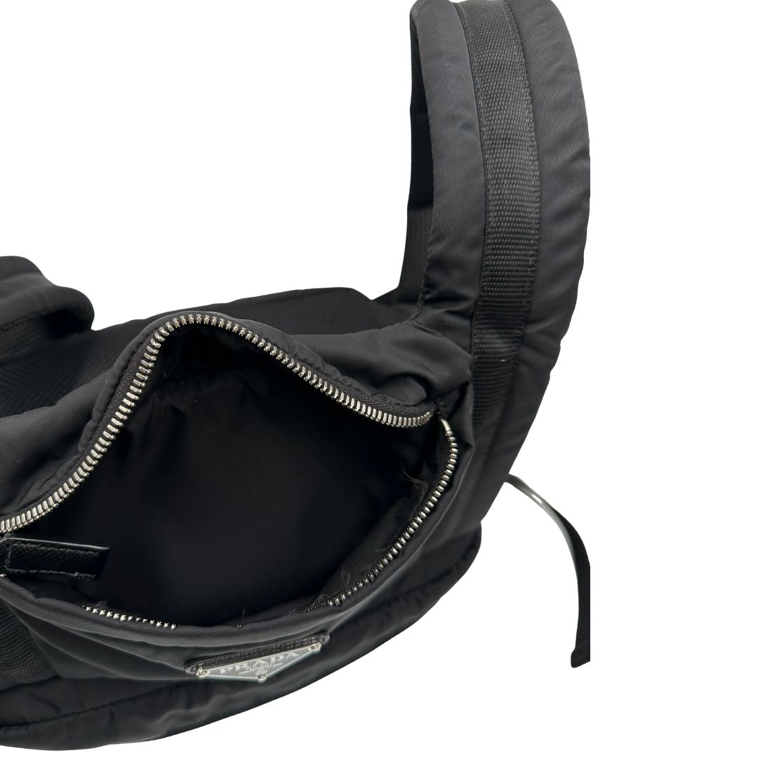 Interno di uno zaino Prada x Adidas in Re-Nylon con chiusura a zip. Struttura con tasca frontale a zip e tasca superiore integrata negli spallacci. Spallacci regolabili con imbottitura e pannello posteriore in mesh. Dettagli con logo triangolo Prada sul lato superiore e branding Prada Re-Nylon e Adidas sul fianco.