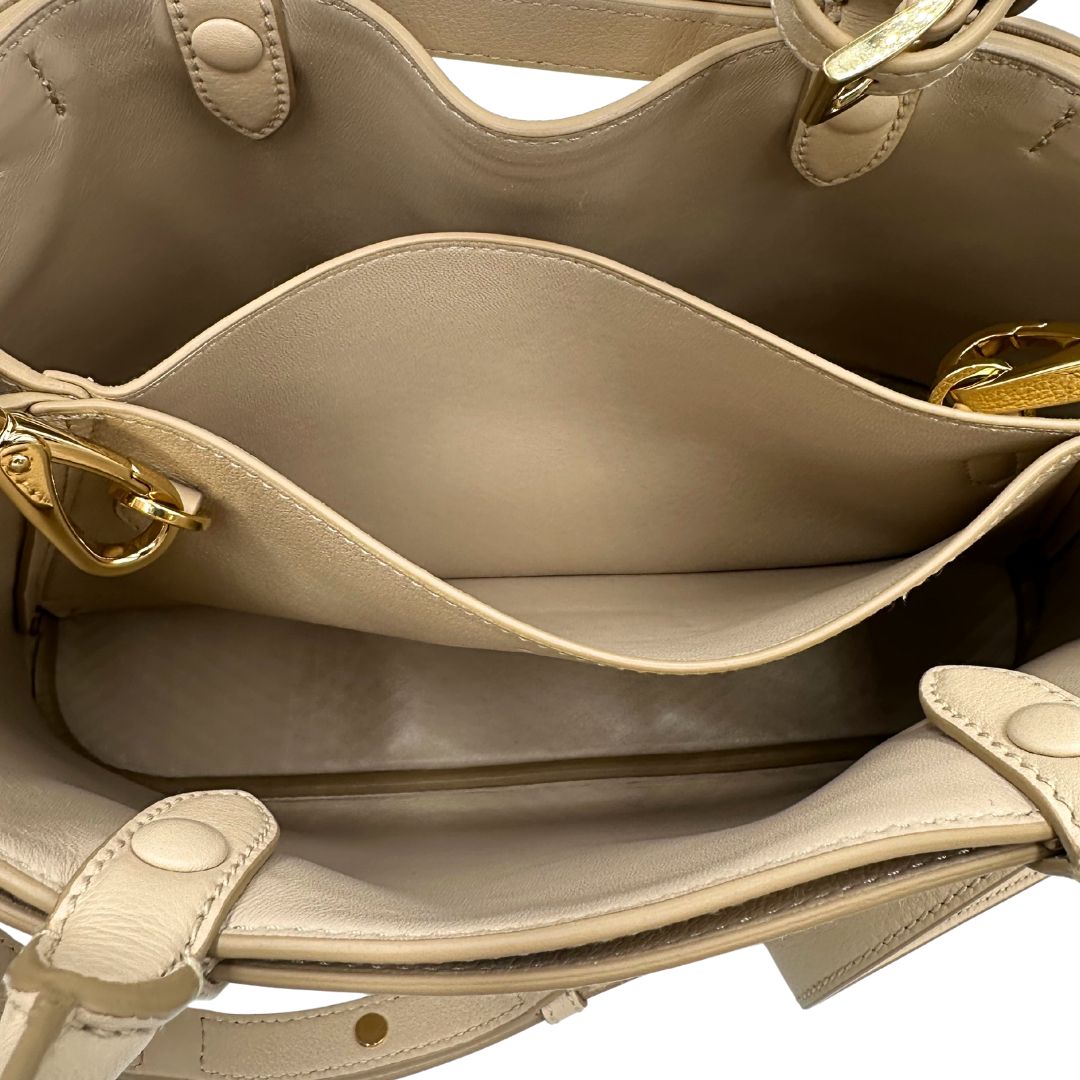 interno Borsa Prada in pelle color travertino con parti metalliche dorate; impreziosita dal logo lettering impresso a caldo in foglia d'oro 22 carati, munita di doppi manici stondati e una tracolla amovibile e regolabile. Completa di corredo, di lusso, eccellenti condizioni, usata. 