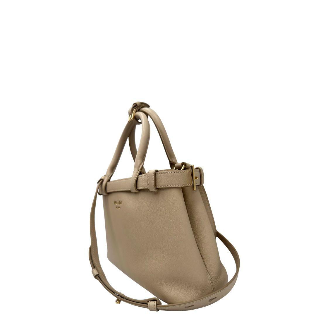 lato Borsa Prada in pelle color travertino con parti metalliche dorate; impreziosita dal logo lettering impresso a caldo in foglia d'oro 22 carati, munita di doppi manici stondati e una tracolla amovibile e regolabile. Completa di corredo, di lusso, eccellenti condizioni, usata. 