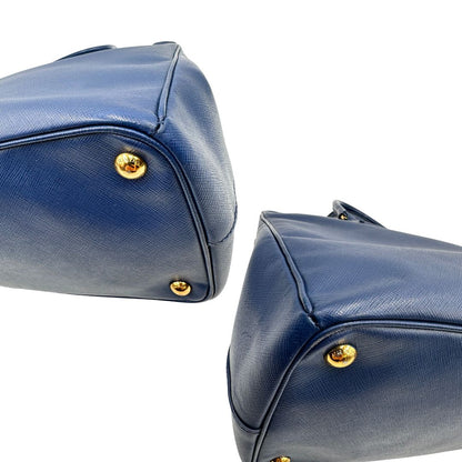 angoli Borsa Prada in pelle saffiano blu con parti metalliche dorate; munita di doppi manici stondati e impreziosita da una clochette portachiavi, di lusso, originale, ottime condizioni. 