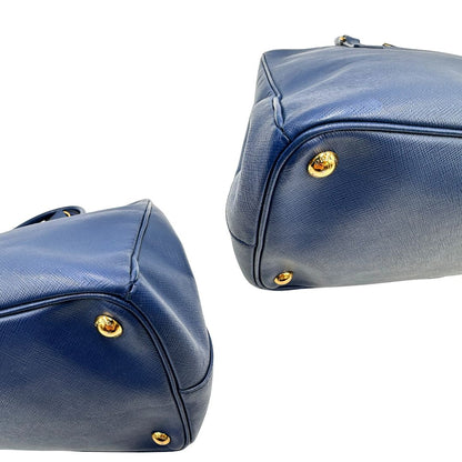 angoli Borsa Prada in pelle saffiano blu con parti metalliche dorate; munita di doppi manici stondati e impreziosita da una clochette portachiavi, di lusso, originale, ottime condizioni. 